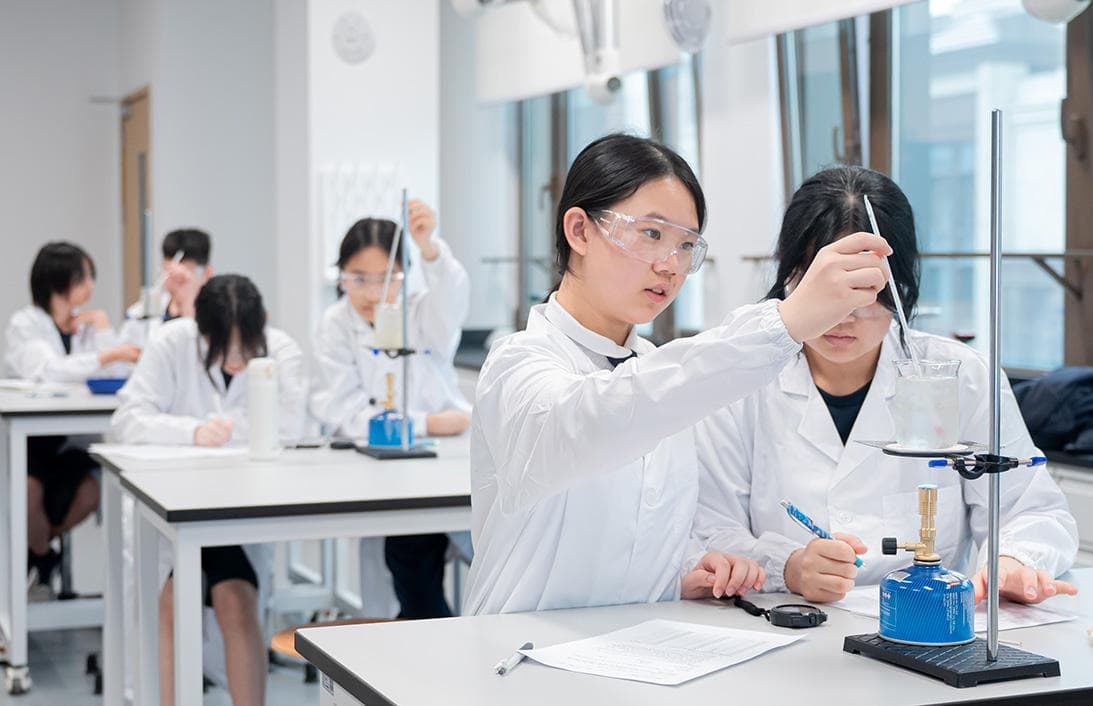 Students in a chemistry laboratory carrying out a titration and recording their observations.